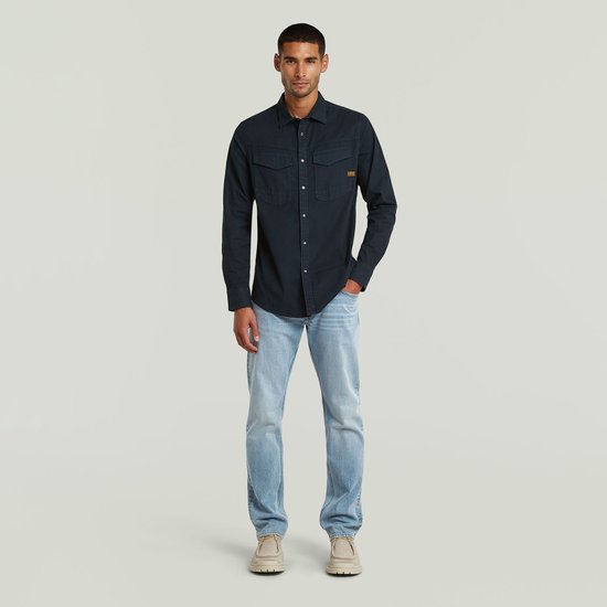Man draagt donkerblauw G-Star overhemd en lichtblauwe jeans.