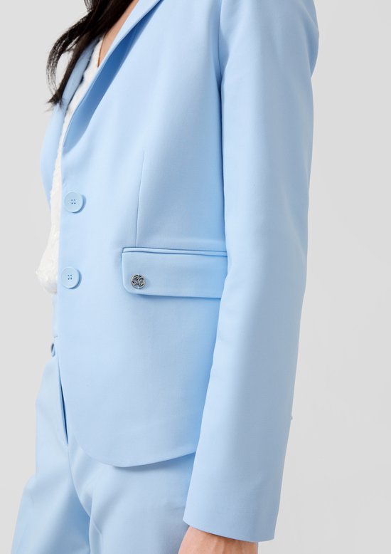 Close-up van lichtblauwe blazer met knopen en zak met '30' embleem.