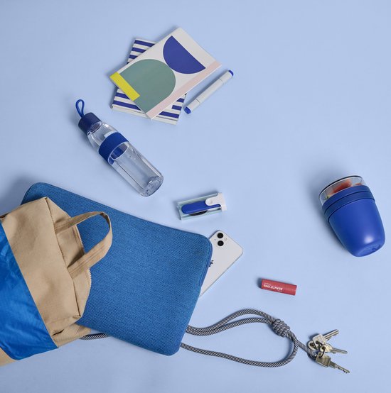 Blauwe Mepal lunchpot en waterfles liggen naast een tas op een lichtblauwe achtergrond.