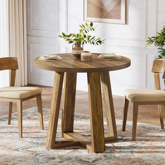 Ronde houten eettafel met X-vormige poot, in een lichte eetkamer met twee stoelen.