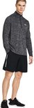 Man draagt zwarte shorts met 'Under Armour' logo aan de zijkant, met een grijs gestreept shirt met rits.