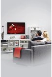 Een koppel heeft een zwarte TV-muurbeugel gemonteerd op een witte muur, terwijl ze naar de TV kijken.