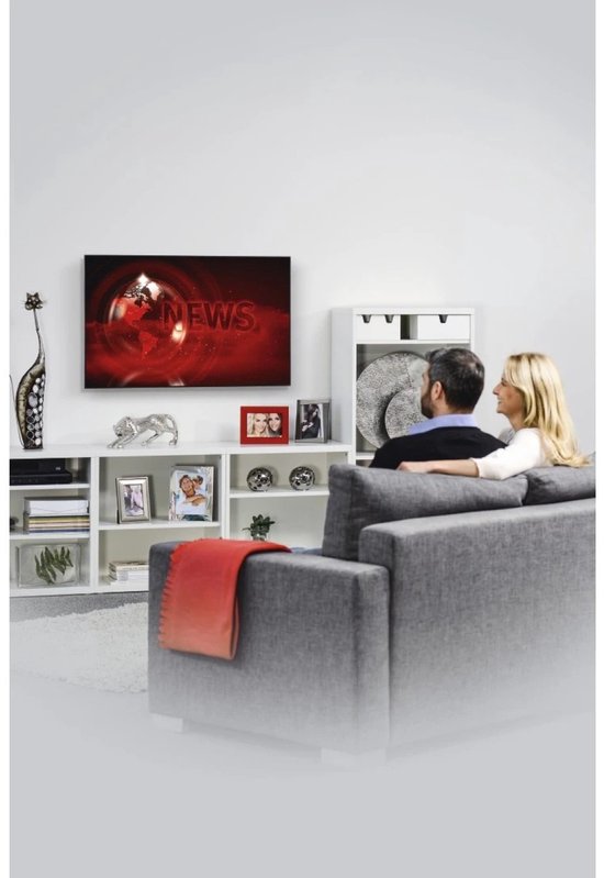 Een koppel heeft een zwarte TV-muurbeugel gemonteerd op een witte muur, terwijl ze naar de TV kijken.