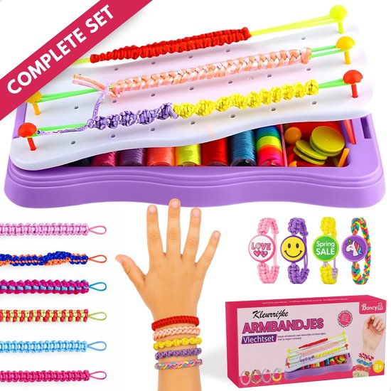 Kindse hand met vier gedragen armbandjes. Naast een doos met 'Boncy Armbandjes' liggen zeven andere creaties.