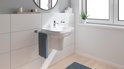 Luxe badkamer interieur met een hangend wastafelmeubel, spiegel, handdoek en plant.