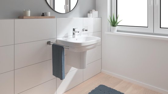 Luxe badkamer interieur met een hangend wastafelmeubel, spiegel, handdoek en plant.