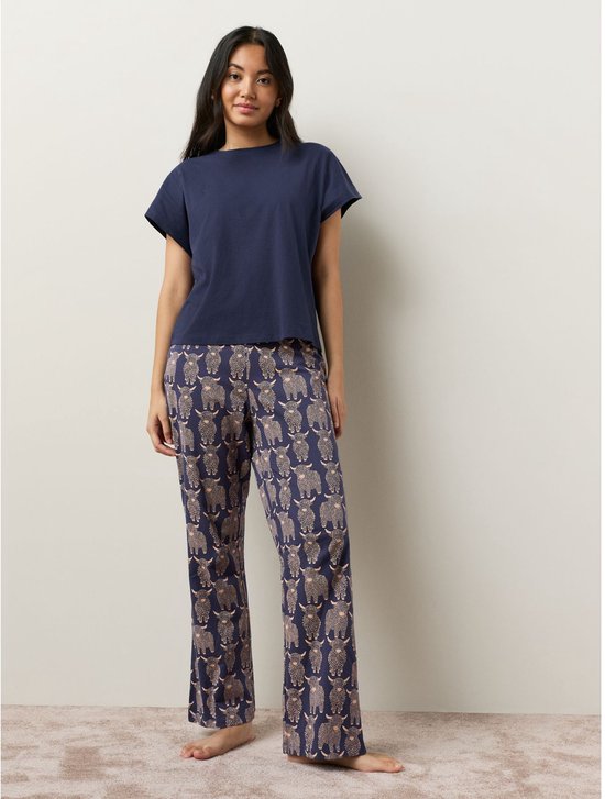 Model draagt een marineblauwe pyjamaset met broek en Schotse hooglanderprint.