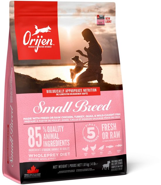 Roze zak Orijen Small Breed hondenvoer met op de voorgrond een silhouet van een vrouw en een hond bij zonsondergang.