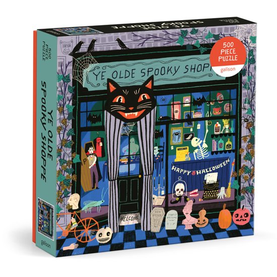 Doos van een 500-delige puzzel, 'Ye Olde Spooky Shoppe', met een zwart met gestreepte kat, een winkelpui met vampiers en skeletten, en "Happy Halloween" tekst.