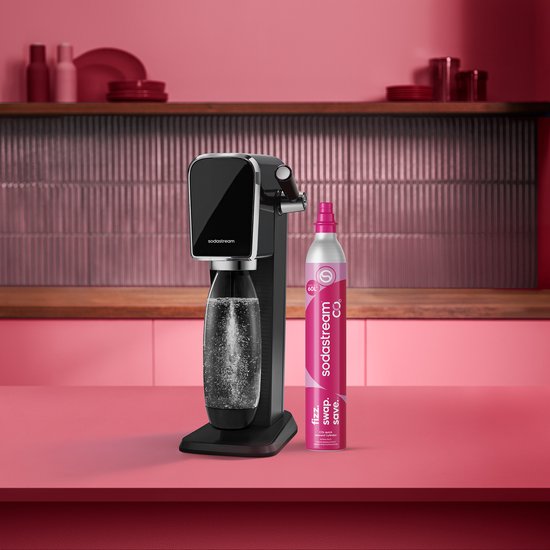 Zwarte Sodastream machine met bruiswaterfles, naast een roze SodaStream CO2-cilinder.