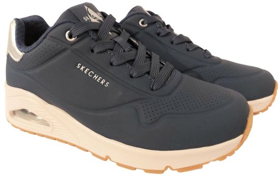 Paar donkerblauwe Skechers sneakers met beige zolen en zilveren details op de hiel.
