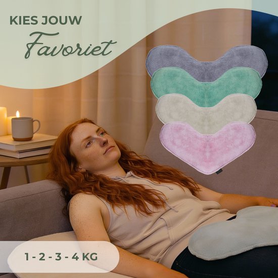 Vrouw met rood haar ligt op een bank en houdt een lichtblauw verzwaringskussen vast. Vijf hartvormige kussens in grijs, mint, beige en roze zijn gestapeld.