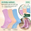 Drie paar antislip sokken in het roze, oranje en lichtblauw met witte noppen op de zool.