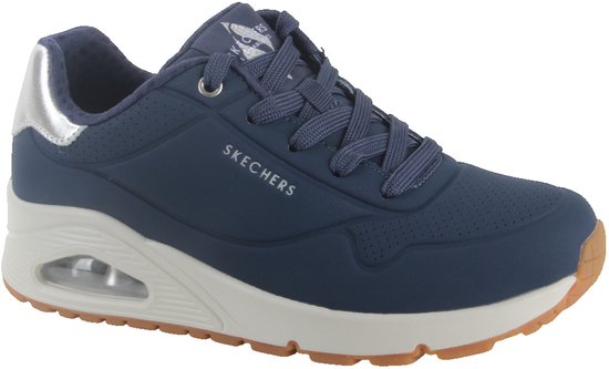 Donkerblauwe sneaker met crèmekleurige zool, zilveren accenten en "SKECHERS" opdruk.