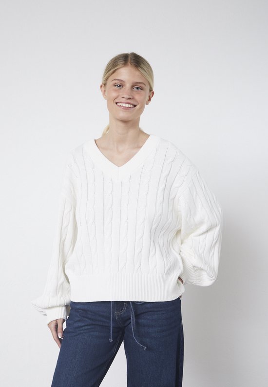 Vue avant d'une femme portant un petit pull blanc en maille torsadée à col en V et un jean.