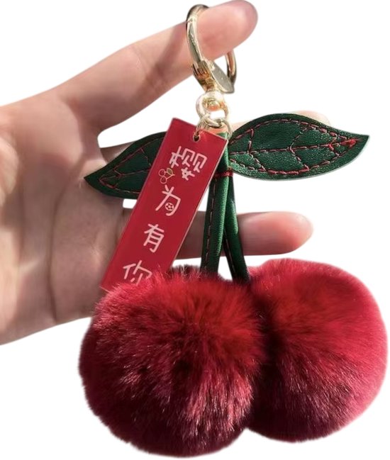 Porte-clés avec deux cerises en peluche rouge foncé avec des feuilles vertes et une étiquette rouge avec du texte chinois.