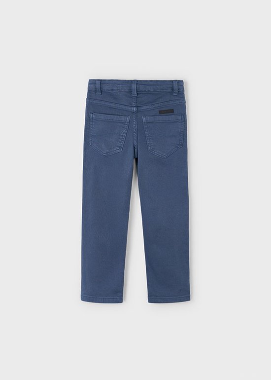 Achterkant van een effen blauwe jongensbroek met vijf zakken en logo patch.