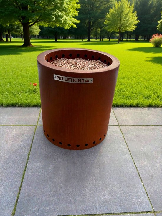 Cortenstalen vuurton van Pellet King gevuld met houtsnippers. Staat op een terras met groen gras en bomen.