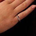 Gros plan d'une bague argentée sertie de zircons sur un doigt.