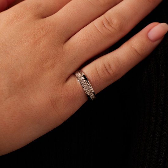 Gros plan d'une bague argentée sertie de zircons sur un doigt.