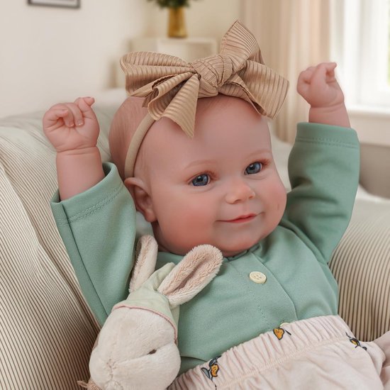 Baby met strik en groen shirt, luierbroekje met olijvenprint en konijntje, met armen omhoog.