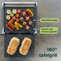 Open contactgrill met gegrilde groenten en spiesjes boven, en twee panini's onder. "180° tafelgrill", "Strak RVS design", "Perfect voor vlees en groente".