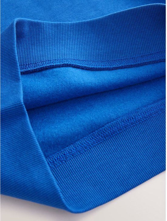 Detail van de geribbelde zoom en de zachte binnenkant van een blauwe trui.