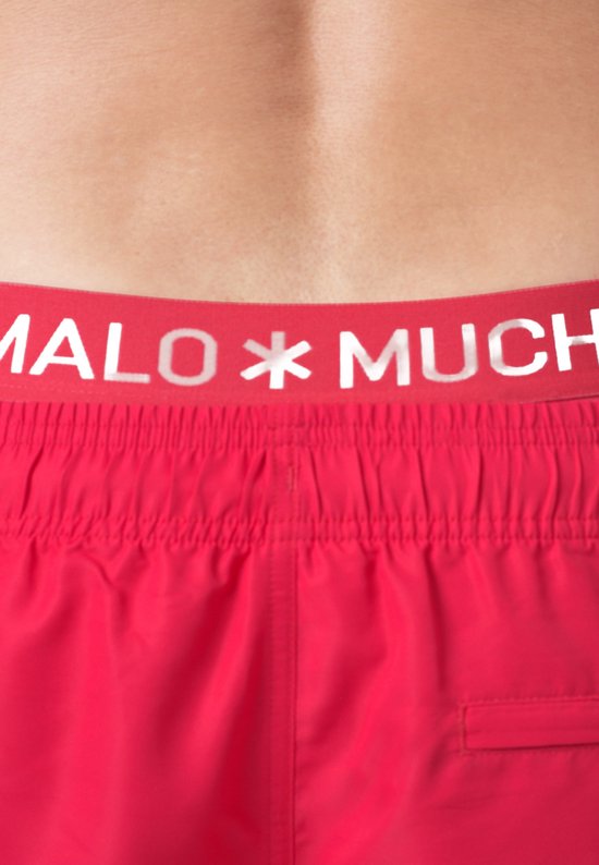 Close-up van de rode tailleband van een zwembroek met de tekst 'MUCHACHOMALO'.