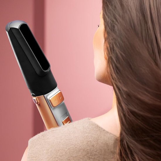 Close-up van een vrouw met bruin haar, gebruikt het mondstuk van een gouden stylingborstel.