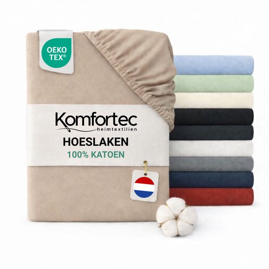 Beige 100% katoenen hoeslaken van Komfortec, OEKO-TEX gecertificeerd. Gestapeld met andere kleuren hoeslakens. Nederlandse vlag op label.