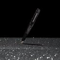 Zwarte glitter Tweezerman pincet schuin op een glinsterende ondergrond.