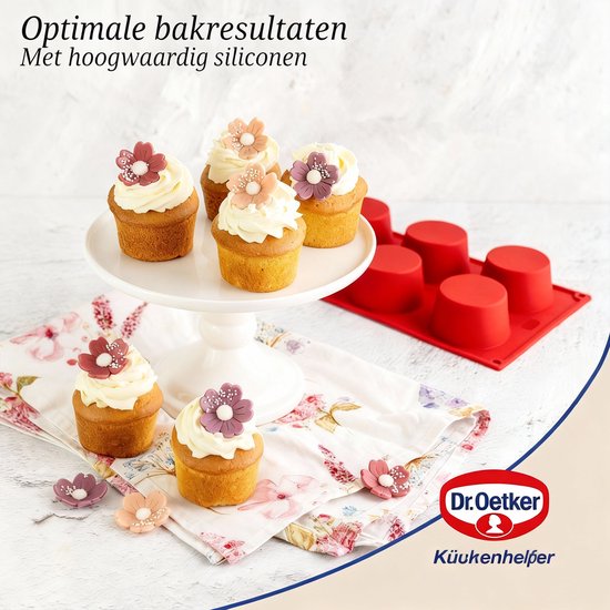 Zes cupcakes met witte frosting en decoratieve bloemetjes, naast een rode siliconen bakvorm. Dr. Oetker logo.