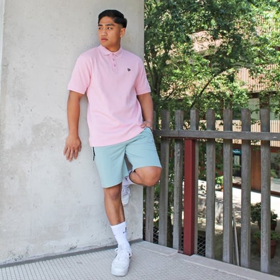 Jonge man draagt een roze poloshirt en lichtblauwe shorts.
