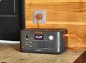 Jackery Explorer 500 powerstation met oranje kabel aangesloten op een stopcontact.