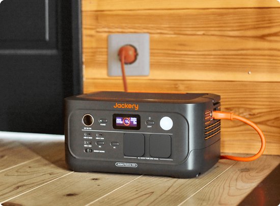 Jackery Explorer 500 powerstation met oranje kabel aangesloten op een stopcontact.