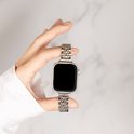 Een hand houdt een zilverkleurig stalen schakelbandje vast, bevestigd aan een Apple Watch.
