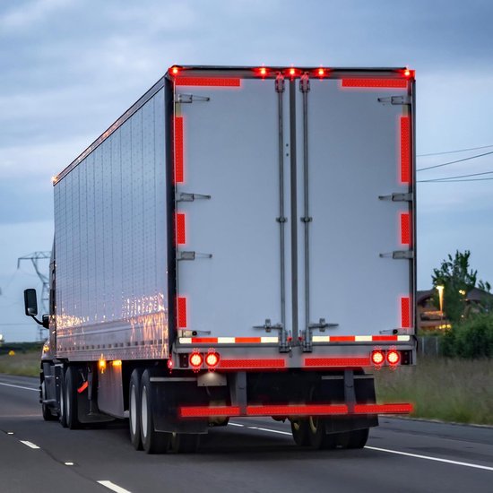 Achterkant van een witte trailer met rode reflecterende tape langs de randen en onderaan.