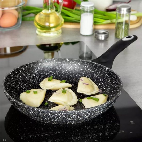 Grijze koekenpan met marmercoating, gevuld met gestoomde dumplings, op een kookplaat.