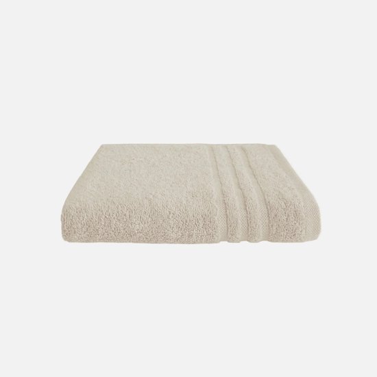 Une serviette de bain beige en tissu éponge, pliée avec des côtes verticales sur le côté droit.