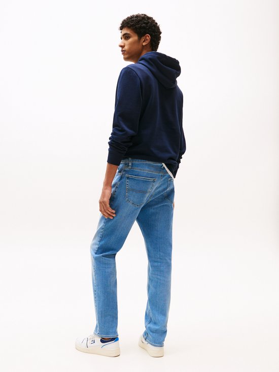 Blauwe jeans met lichte wassing, gedragen door een man van achteren.