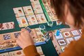 Speler legt een kaart neer in het bordspel Coffee Rush, met zicht op de speelborden en pionnen.