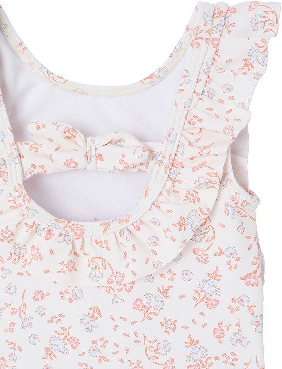 Detail van het witte badpak met rugopening, strik en bloemenprint.