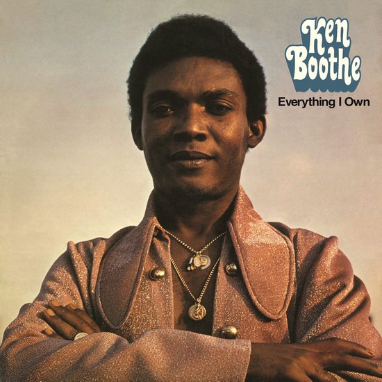 Ken Boothe, zanger, draagt een glinsterend roze jasje en gouden kettingen.