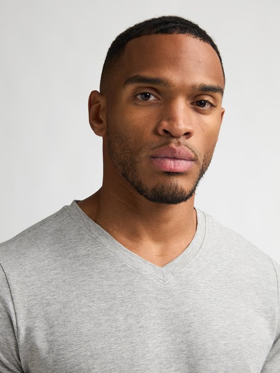 Close-up van een man die een effen lichtgrijs T-shirt met V-hals draagt.