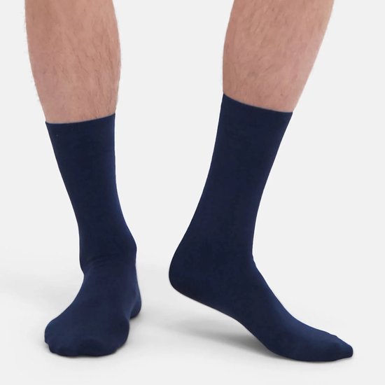 De benen van een man met donkerblauwe, halfhoge sokken. De sokken hebben een gladde afwerking.