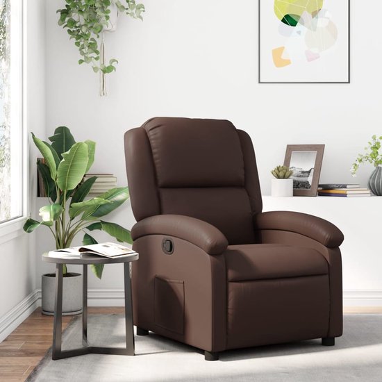 Bruine kunstlederen fauteuil in een woonkamer. Naast een bijzettafel en planten, met een schilderij aan de muur.