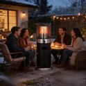 Zwarte staande terrasverwarmer met zilverkleurige details, met vlammen in de glazen buis, op een patio met sneeuw en mensen.
