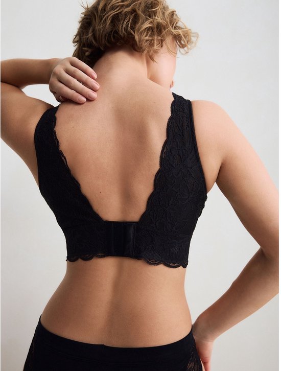 Achterkant van een zwarte kanten bralette met v-uitsnijding en haaksluiting.