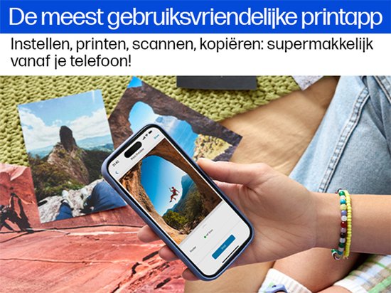 Hand met smartphone toont printapp op een bureau met foto's.