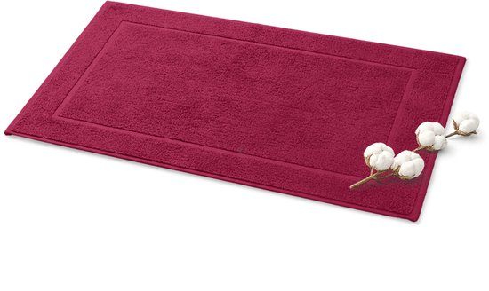 Fuchsia badmat met een subtiel kader en een takje katoen ernaast.